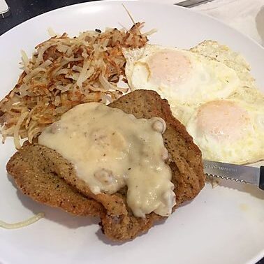A plate of food with eggs, hash browns and meat.