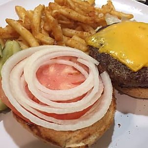 A hamburger with onions and tomato on it.